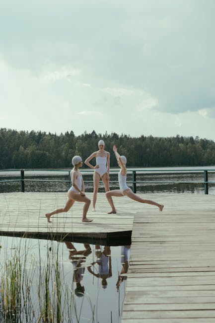 Woman performing a calm yoga pose on a wooden pier by the lake at sunrise